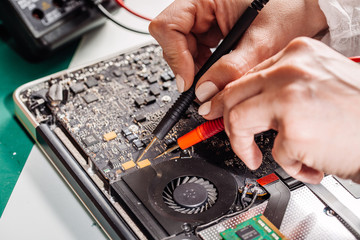 Naklejka premium woman repairing laptop computer in service center. Repairing and fixing service in lab. Electronics repair service concept.