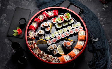 Japanese cuisine. Asian food. Sushi set on a wooden round plate. Stone background.