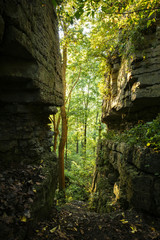 Rock path surrounded by trees and rock formations and fall leaves at evening light, High Cliff Park, Wisconsin