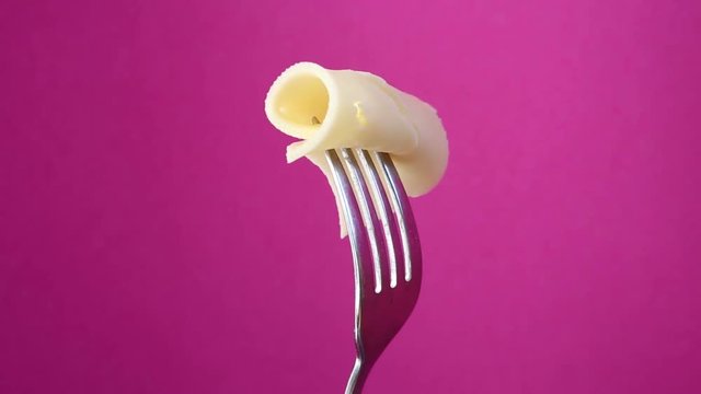 rotating fork with slice of cheese on purple background
