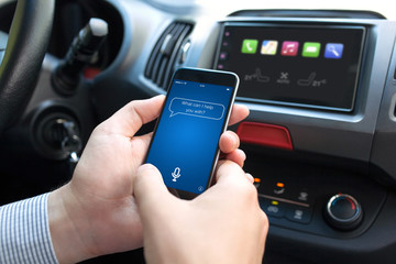 man hand in car holding phone with app personal assistant