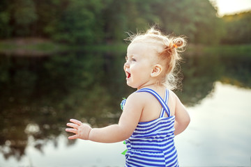 Cheerful baby girl playing near the lake. The concept of childhood, leisure and lifestyle.