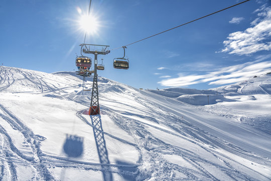 Skiers on the chairlift in high mountains during sunny day