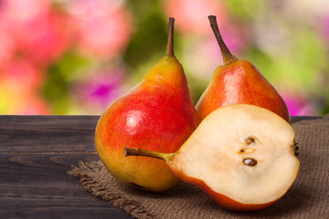 two whole and half of pear on a wooden table with cloth burlap