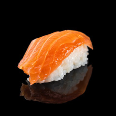 Japanese classic sushi nigiri with salmon isolated on black background with reflection, close up