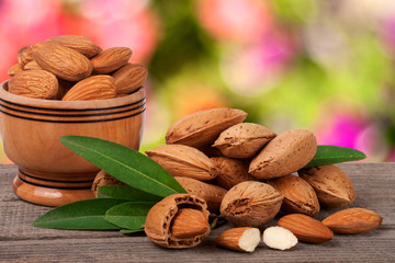 almonds in a bowl on the old wooden board with blurred garden background