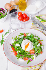 Fresh salad with arugula, mozzarella, cherry tomatoes and poached egg