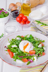 Fresh salad with arugula, mozzarella, cherry tomatoes and poached egg