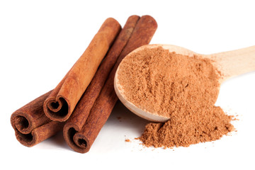 three cinnamon sticks and powder with spoon isolated on white background