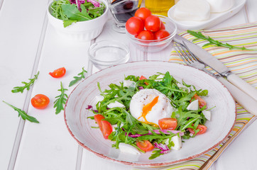 Fresh salad with arugula, mozzarella, cherry tomatoes and poached egg