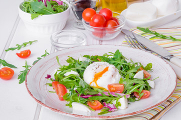 Fresh salad with arugula, mozzarella, cherry tomatoes and poached egg