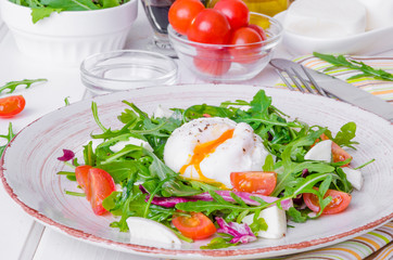 Fresh salad with arugula, mozzarella, cherry tomatoes and poached egg