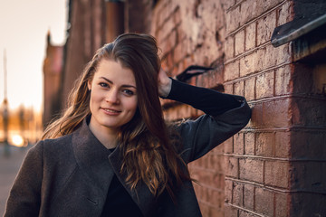 Young attractive girl in a coat in the city at sunset