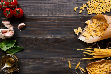 Dried mixed pasta and vegetables on the dark wooden table top view