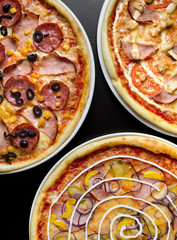 Three different pizzas on a white plate and a black table