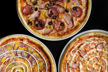 Three different pizzas on a white plate and a black table