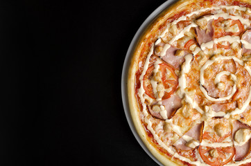 Pizza with chicken and vegetables on a white plate and a black table