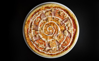 Pizza with chicken and vegetables on a white plate and a black table