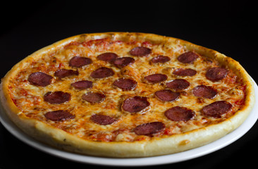 Pizza with salami on a white plate