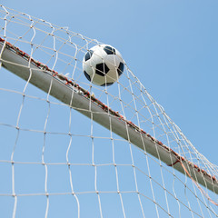 soccer ball in goal. isolated on blue sky background.