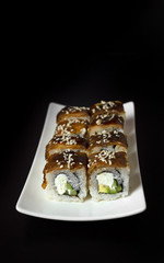 Sushi with eel on white plate on a black background