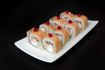 Sushi rolls with young cheese and trout on a black background