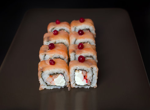 Sushi rolls with young cheese and trout on a black background
