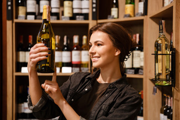 Happy lady in supermarket choosing alcohol