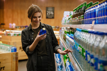 Happy woman in supermarket choosing water.