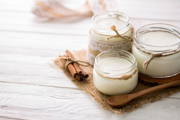 Yogurt in glass jars on wooden background