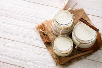 Yogurt in glass jars on wooden background
