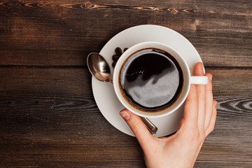cup with a drink in hand, saucer and a teaspoon