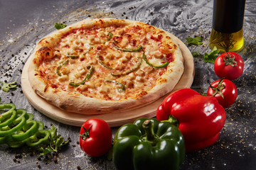 whole italian pizza on wood table with ingredients in black table