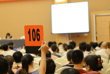 People holding auction paddle to buy from auction.