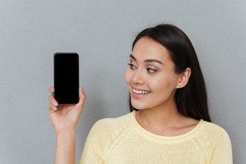 Portrait of smiling pretty young woman with blank screen smartphone