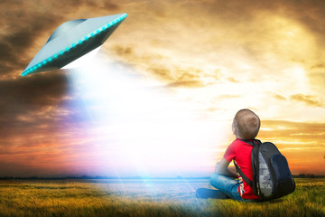The little boy looks up at an unidentified flying object which appeared in the sky. © Denis
