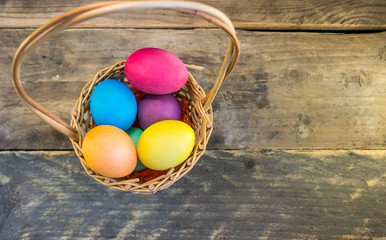 Basket with colorful easter eggs on wooden table . Happy Easter