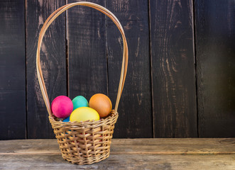 Basket with colorful easter eggs on wooden table