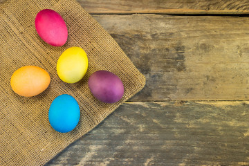 Colorful easter eggs with sack on wooden table