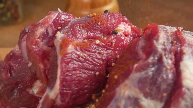Close up of spices falls on the leg of lamb in slow motion