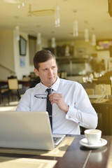 Young businessman sitting in cafe with laptop