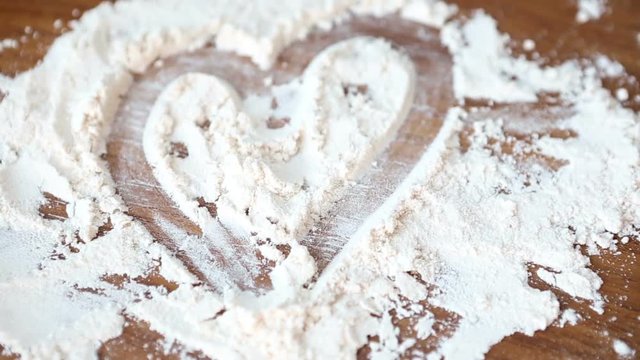 heart drawn with flour on rotating wooden board
