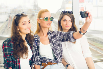Three girls stand at the airport and looking at the tablet. A trip with friends.girls doing selfie