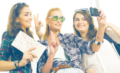 Three girls stand at the airport and looking at the tablet. A trip with friends.girls doing selfie