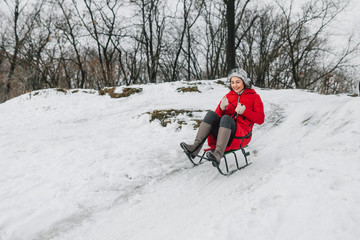 The girl walks in one of winter days in the beautiful park. She has wanted to sweep on the sledge. The girl slides from a hill and she is overflowed by emotions. Very cheerful photo.