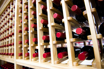Group of red wine bottles stacked on wooden racks.