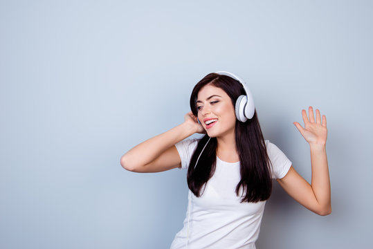 Happy young girl listening to music in headphones and dancing