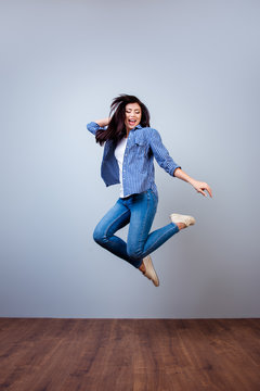 Vertical portrait of pretty young woman in checkered shirt jumping up
