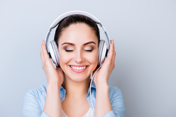 Fototapeta premium Portrait of relaxed pretty woman listening to music in headphones isolated gray background