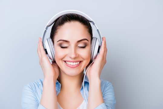 Portrait of relaxed pretty woman listening to music in headphones  isolated gray background